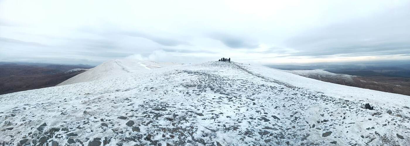 Grupo pequeno no cume nevado das Highlands escocesas, ao entardecer